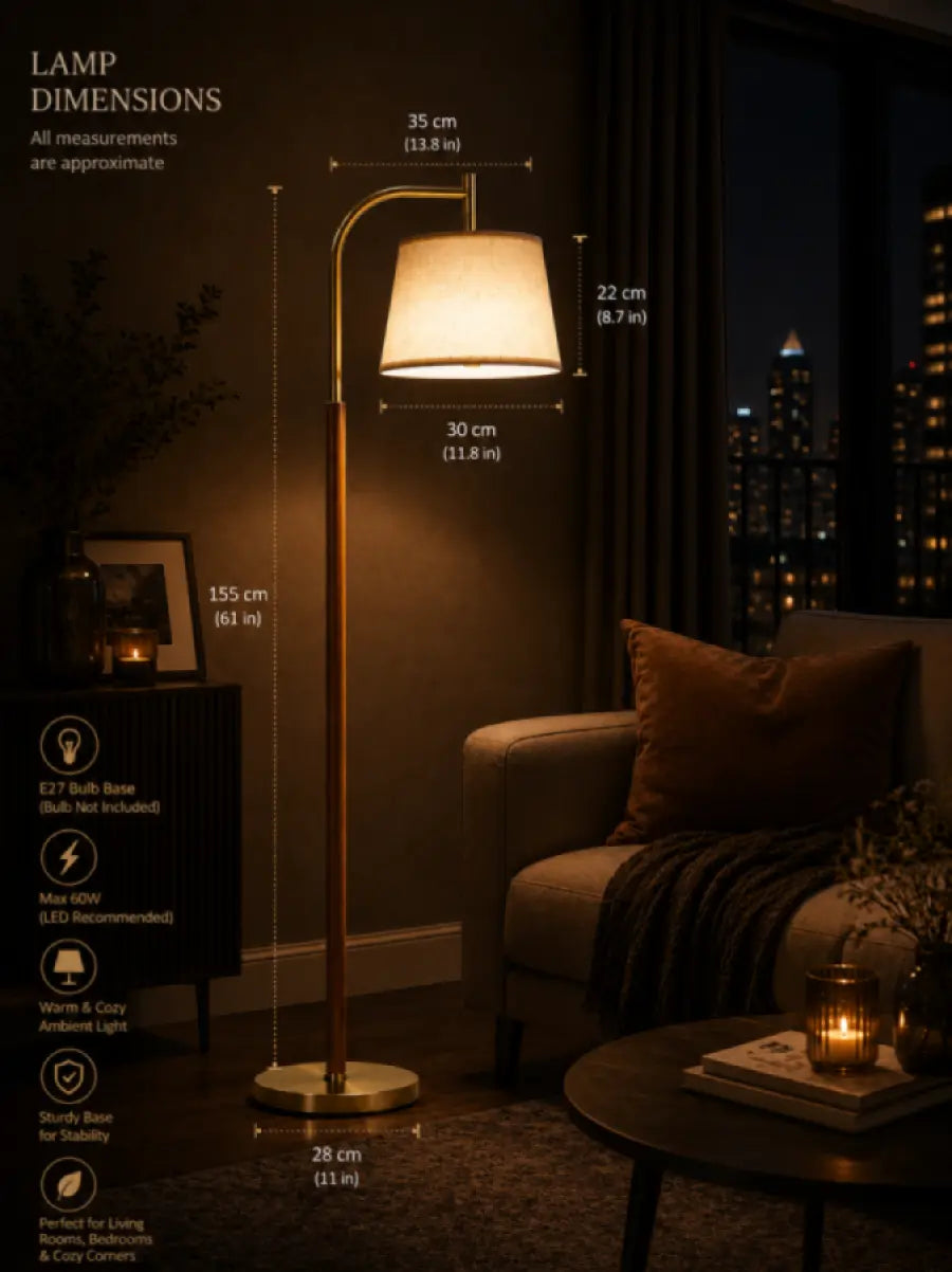 A floor lamp shown in a dimly lit living room scene with overlaid dimension labels and product specs. The lamp has a warm white drum shade, a slim warm metallic stand, and a round base.
