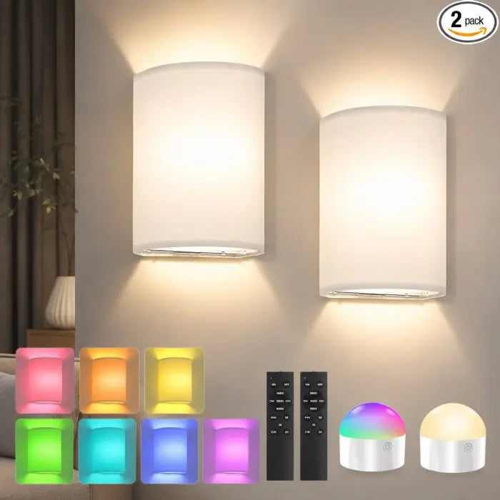 Two white cylindrical wall sconces mounted on a beige wall, glowing with warm light. The image includes a '2 pack' badge, small color-changing light cubes, two black remote controls, and two small dome-shaped smart bulbs at the bottom, indicating a multi-light smart bulb set.
