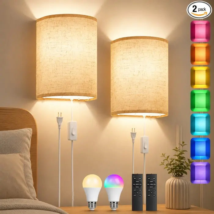 Two wall-mounted drum lamp shades with beige woven fabric, shown lit in a bedroom setting above a nightstand. The image includes two E14 LED bulbs, two black remote controls, a small potted plant, and a vertical color-changing light indicator graphic on the right labeled '2 pack'.