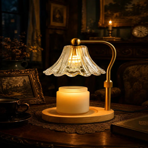 A vintage-style table lamp with a clear ribbed glass bell shade, a curved brass arm, and a warm white candle jar on a round wooden base, placed on a dark wooden table in a dimly lit room.