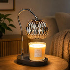 Black candle warmer lamp with timer and dimmer warming a scented jar candle on a wooden table in a modern living room