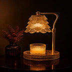 A warm amber table lamp with a tiered crystal shade and a matching crystal candle holder on a round base, set on a dark reflective surface with a small vase of dried stems beside it.
