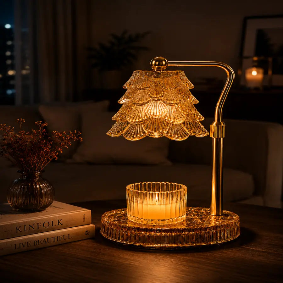 A decorative table lamp with a tiered clear glass shade and a lit candle in a matching ribbed glass holder, set on a wooden table in a warmly lit living room.