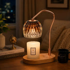 Black candle warmer lamp with timer and dimmer warming a scented jar candle on a wooden table in a modern living room