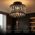 A cylindrical ceiling light fixture with a black metal frame and clear faceted crystal panels, shown hanging in a dimly lit modern interior. Three feature callouts at the bottom highlight premium crystal, warm ambient light, and durable metal.