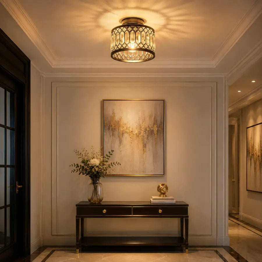 A cylindrical ceiling light fixture with a warm glowing crystal-like shade and dark metal frame, mounted on a white ceiling in an elegant hallway with a console table and abstract wall art.