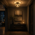 A warm, atmospheric hallway scene featuring a decorative cylindrical ceiling light with a black metal cage and warm yellow light, mounted above a dark wood console table with a framed abstract painting and a lit candle.