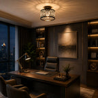 A modern office interior with a dark wood desk, black leather chair, built-in shelving with warm lighting, a large abstract wall art piece, and a decorative cylindrical ceiling light casting a warm glow.