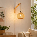 A warm, glowing woven rattan pendant light hangs from a curved natural wood wall sconce in a cozy, sunlit living room setting.