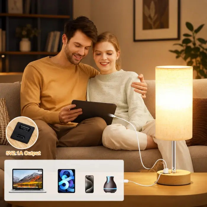 Modern bedside table lamp with USB charging port, 3-way dimmable touch control, linen fabric shade, and wooden base on a bedroom nightstand with warm ambient lighting.