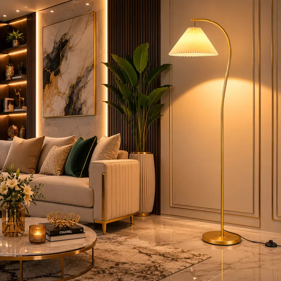 A modern gold arched floor lamp with a warm glowing shade stands in a luxurious living room next to a beige sofa and a large potted plant.