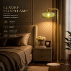 Luxury floor lamp with a gold-finished metal frame and a textured green glass shade, shown illuminated in a modern bedroom setting next to a bed with a bedside table.