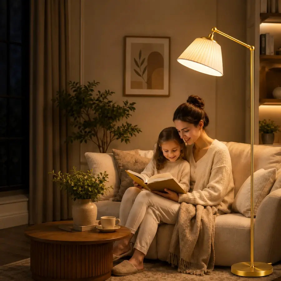 A woman and a child sit on a beige sofa in a warmly lit living room, reading a book together. A tall floor lamp with a gold-toned frame stands beside them, casting light over the scene.