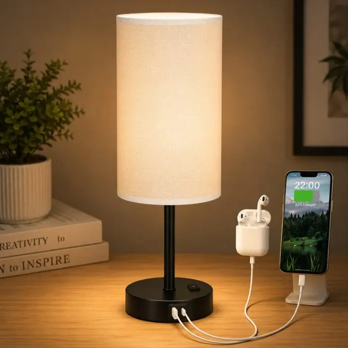 Modern bedside table lamp with USB charging port, 3-way dimmable touch control, linen fabric shade, and wooden base on a bedroom nightstand with warm ambient lighting.