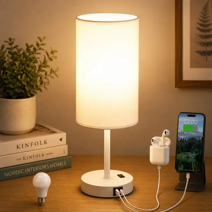 Modern bedside table lamp with USB charging port, 3-way dimmable touch control, linen fabric shade, and wooden base on a bedroom nightstand with warm ambient lighting.