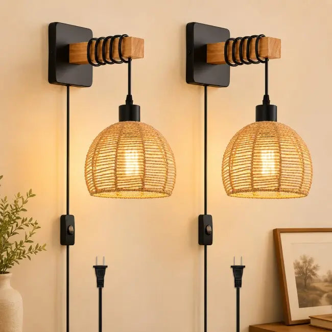 Two matching wall-mounted pendant lights with black metal wall plates, wooden accents, and woven rattan shades, shown lit against a warm beige wall.