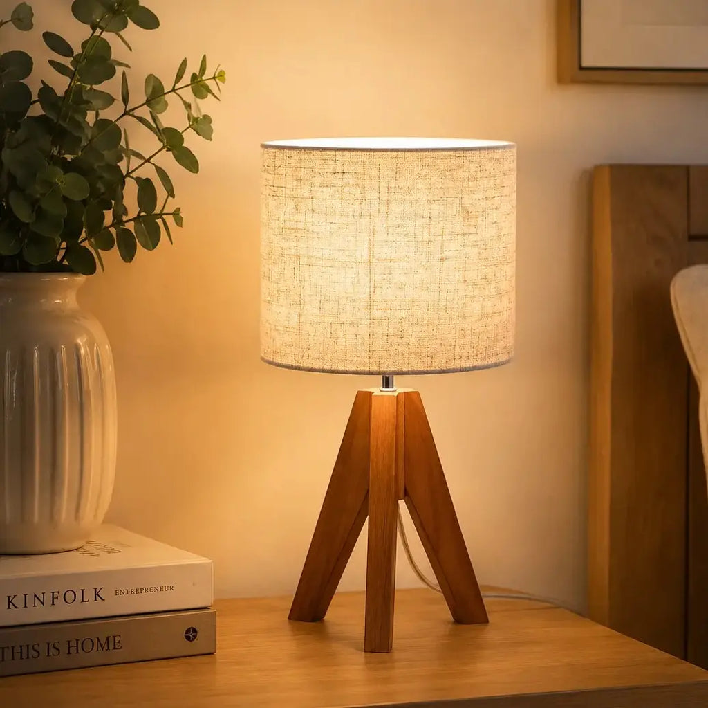 Modern wooden tripod table lamp with linen fabric shade on a bedside table, perfect for bedroom, living room and cozy home lighting